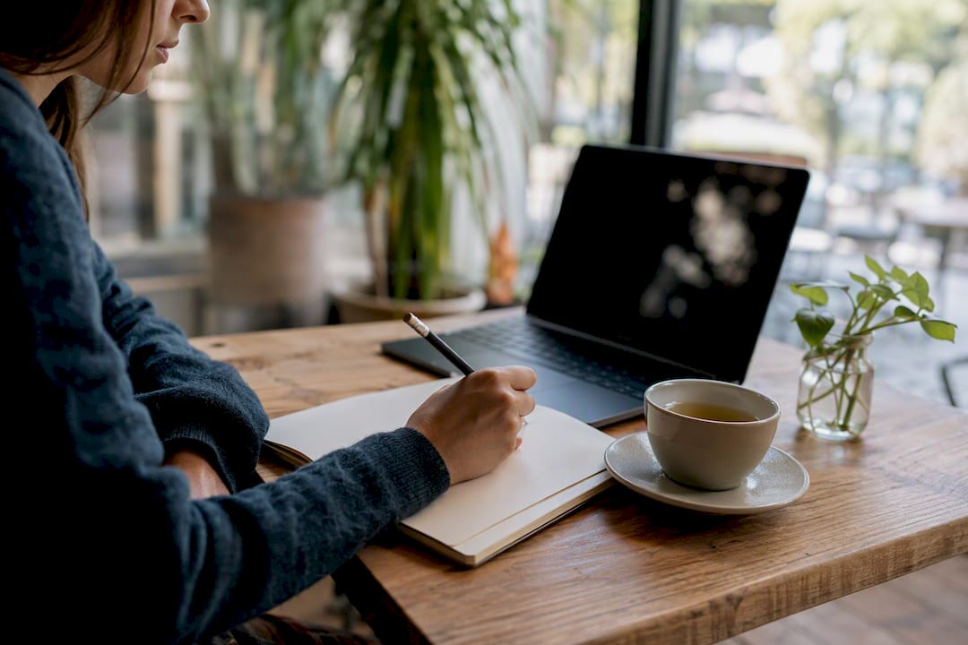 Hand writing buying guide notes in workspace